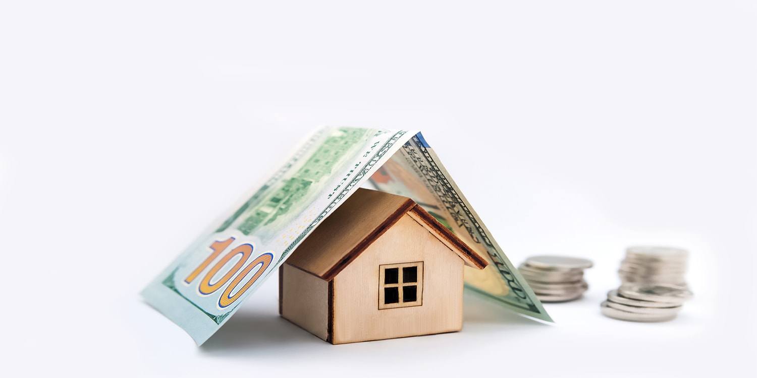 100 dollar bill folded over wooden house to represent cash home sale concept.